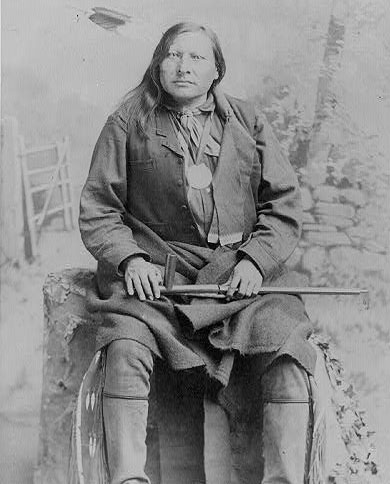 Photo: Portrait of Spotted Elk, full length, seated, facing slightly left; holding peace pipe.